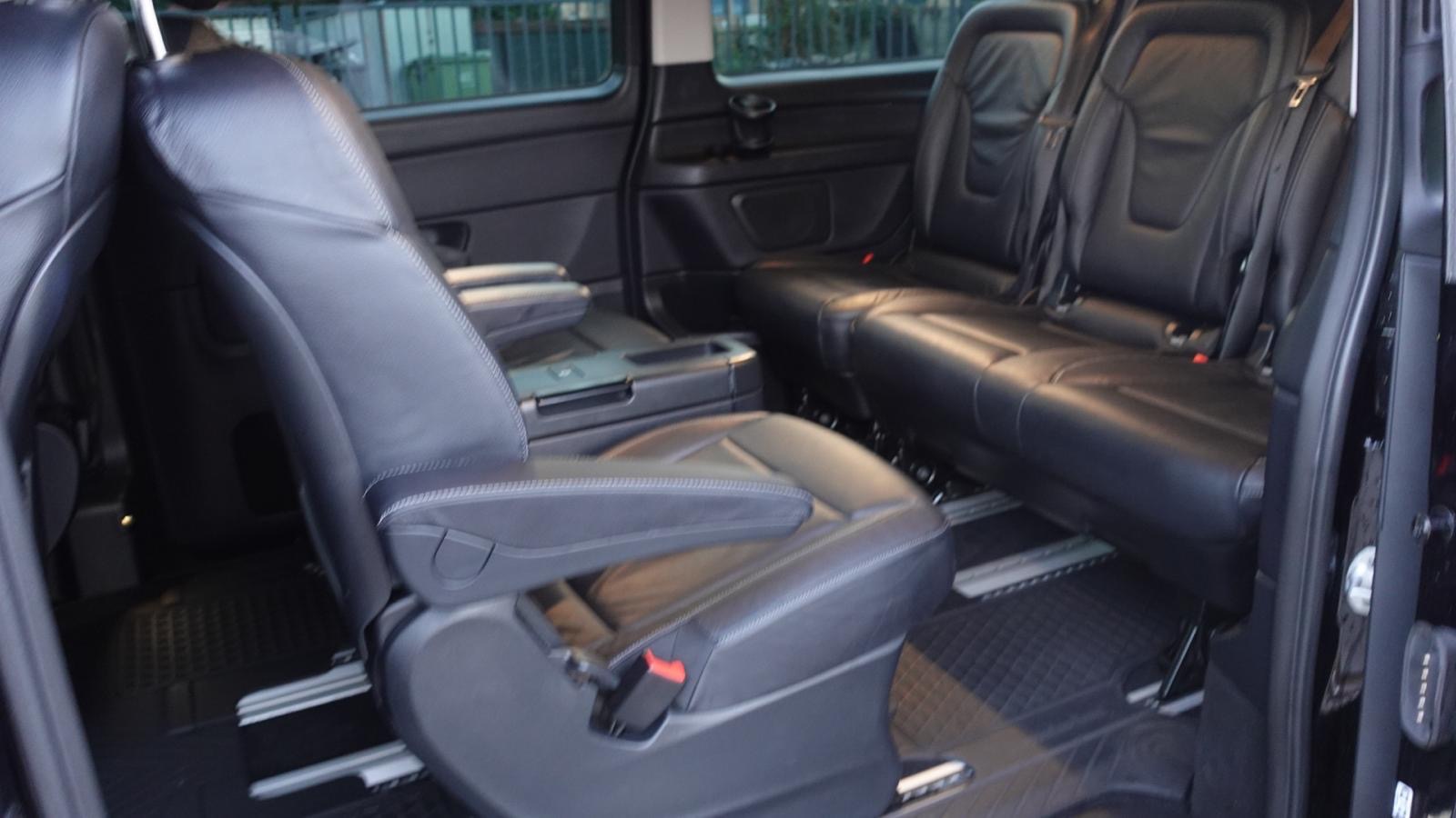 Wnętrze luksusowego, czarnego vana z skórzanymi siedzeniami, widoczne z otwartych drzwi. Komfort i przestrzeń dla pasażerów.