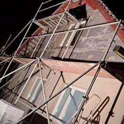 Krystian Drozdowski - Dom w trakcie prac elewacyjnych nocą, widoczne rusztowania, płyty izolacyjne i przygotowana powierzchnia pod tynk.