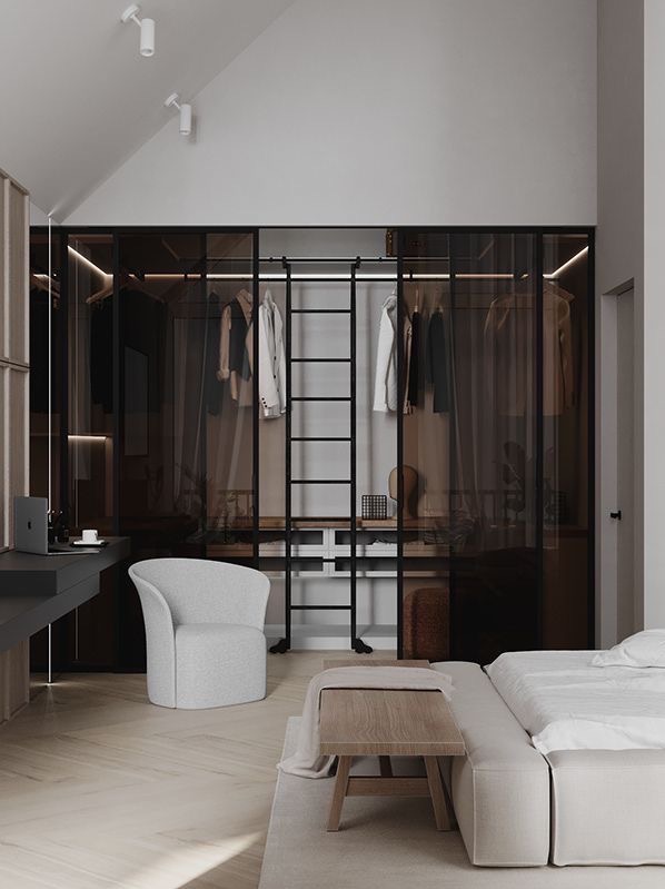 Nowoczesna garderoba z przesuwnymi, przydymionymi szklanymi drzwiami w czarnych ramach, wyposażona w drabinkę, widoczna z perspektywy sypialni z minimalistycznym wystrojem i biurkiem z laptopem.