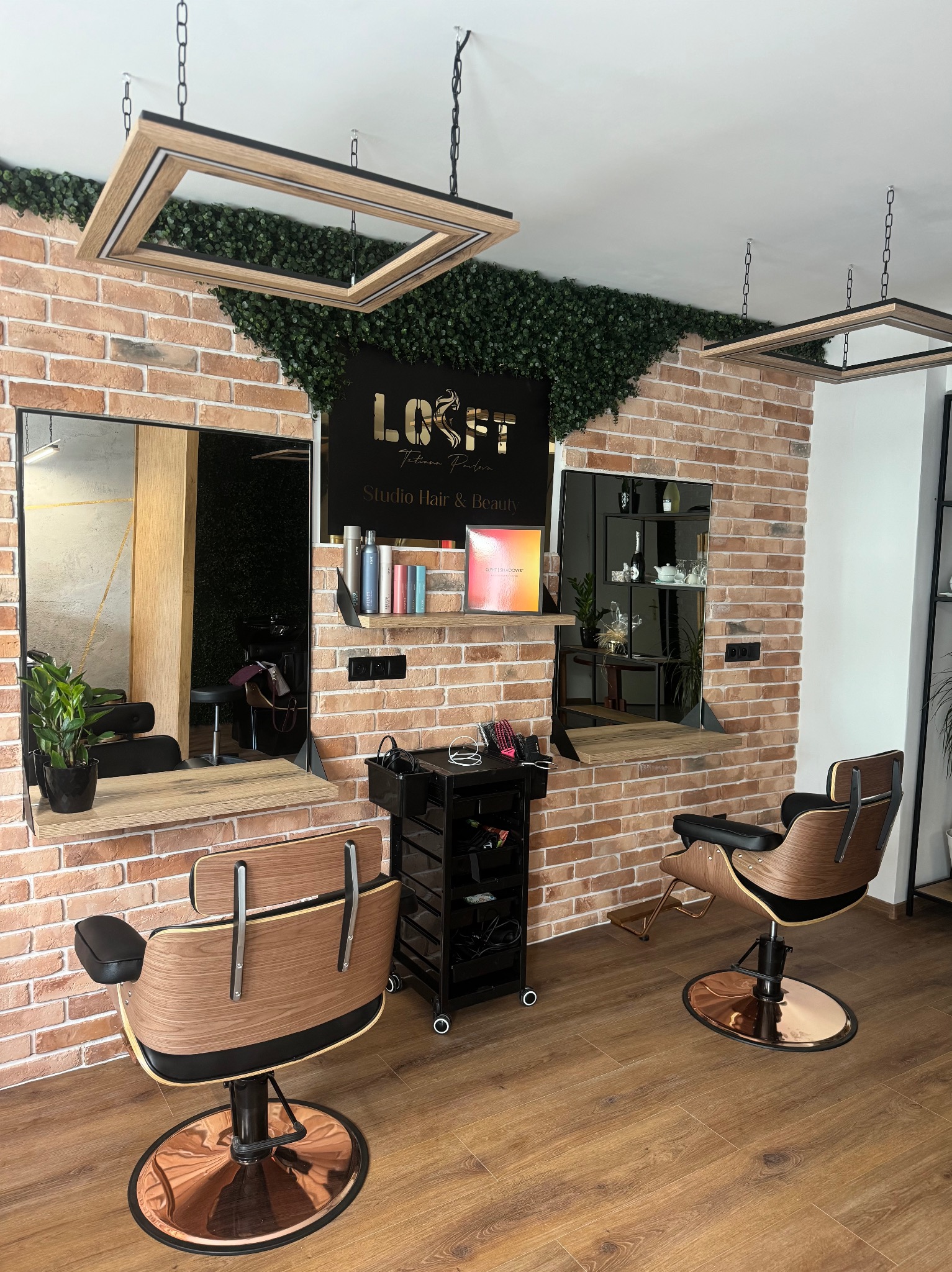 Nowoczesne wnętrze salonu fryzjerskiego z ceglaną ścianą, drewnianymi blatami i designerskimi fotelami fryzjerskimi na miedzianych podstawach. Oświetlenie w stylu loft.