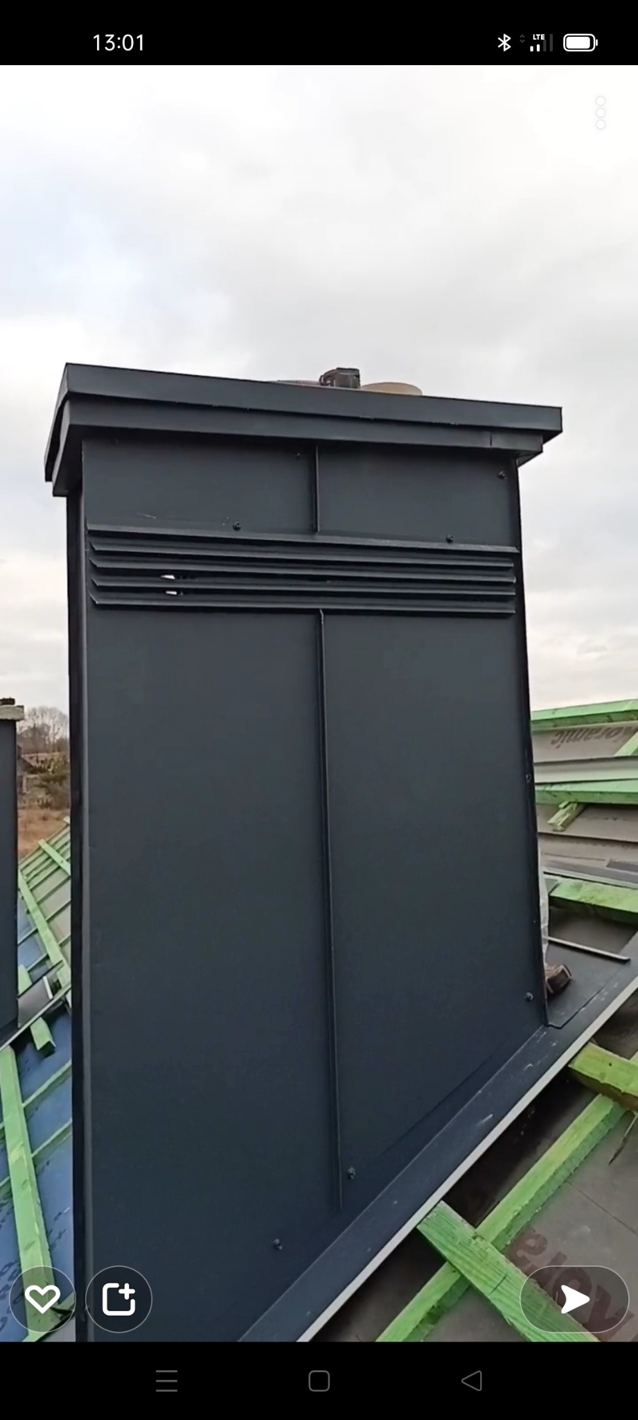 Nowoczesny, grafitowy komin z blachy na dachu z widoczną konstrukcją drewnianą i membraną dachową.