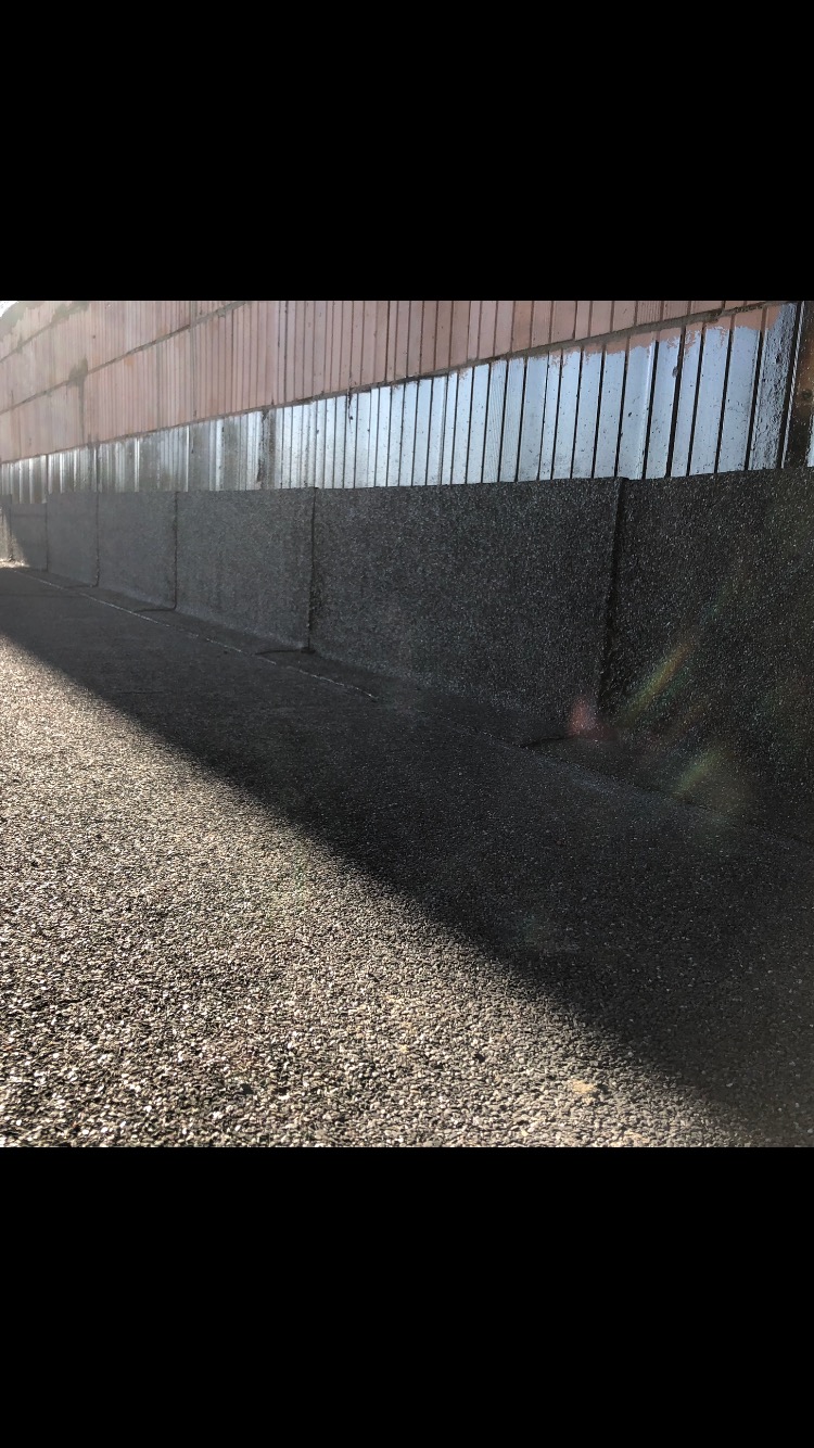 Szczegółowe ujęcie dachu pokrytego papą termozgrzewalną, widoczne łączenia i faktura materiału, z fragmentem ściany w tle.