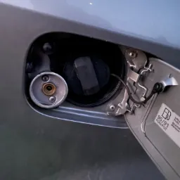 Otwarty wlew paliwa w samochodzie z widocznym adapterem do tankowania gazu LPG.