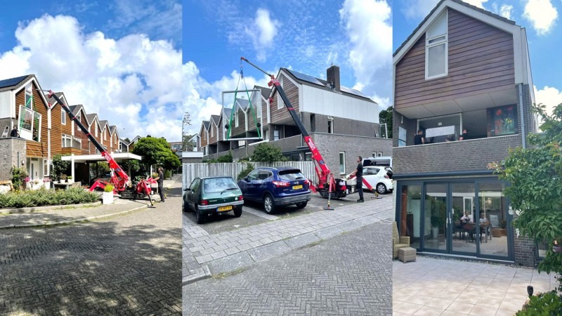 Montaż okna za pomocą dźwigu na zewnątrz budynku mieszkalnego w słoneczny dzień.