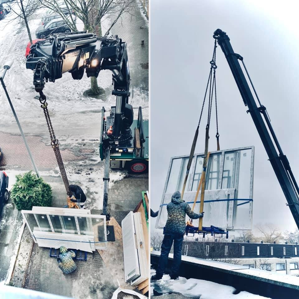 Montaż okien za pomocą dźwigu w Lisse, widok z góry na plac budowy z ośnieżonym otoczeniem miejskim.