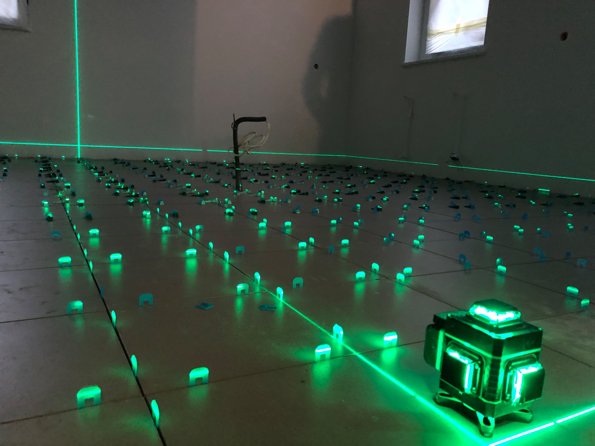 Położone płytki podłogowe, wyrównane za pomocą klipsów i lasera krzyżowego, widoczne okno w tle.