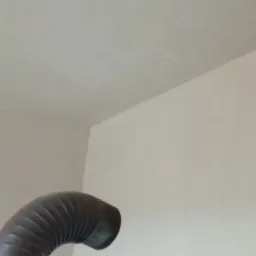 Świeżo położony jasny tynk na ścianach wewnętrznych, widoczne ślady po łataniu, w rogu pomieszczenia wystaje fragment rury.