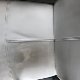 Porównanie: Połowa jasnej, skórzanej kanapy wyczyszczona, ukazująca wyraźną różnicę w czystości i barwie materiału.