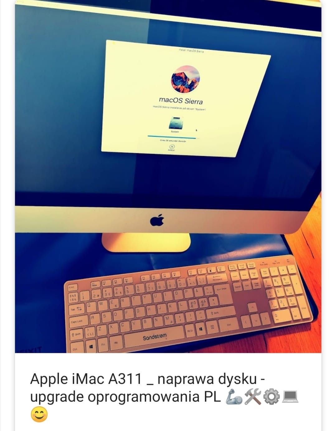 Ekran iMac z uruchomionym procesem instalacji macOS Sierra, widoczna klawiatura Sandstrom na niebieskim podłożu.