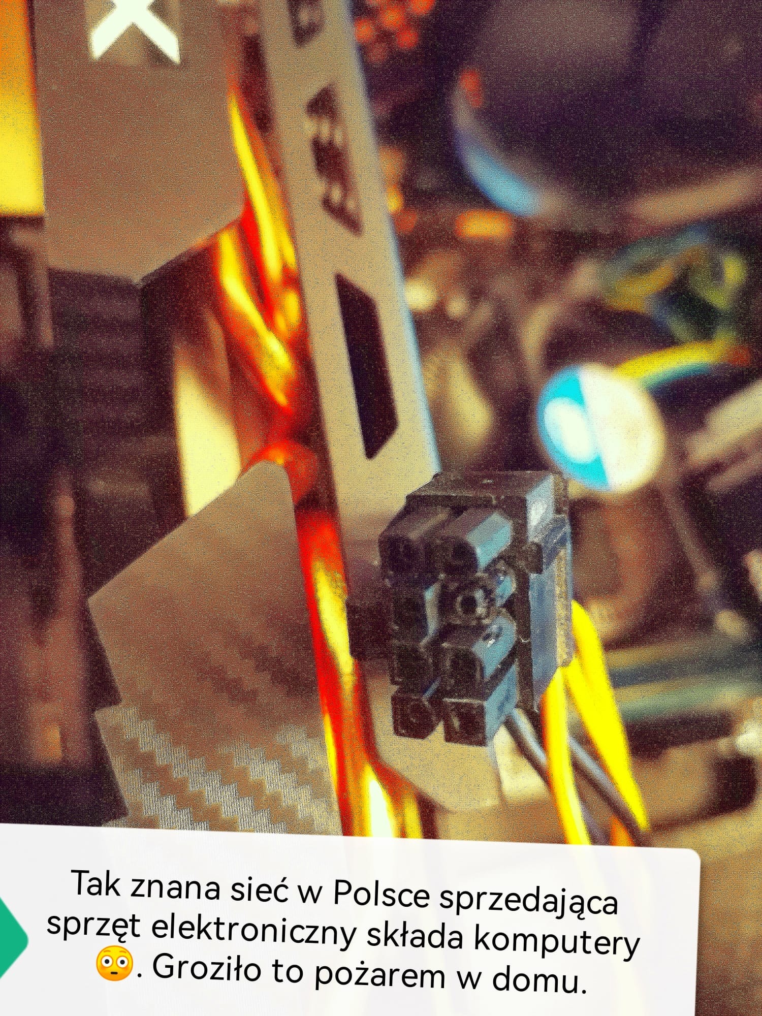 Czarny wtyk zasilania ATX z żółtymi kablami wewnątrz komputera, z widocznym fragmentem obudowy i kartą graficzną w tle, z informacją o potencjalnym zagrożeniu pożarowym.