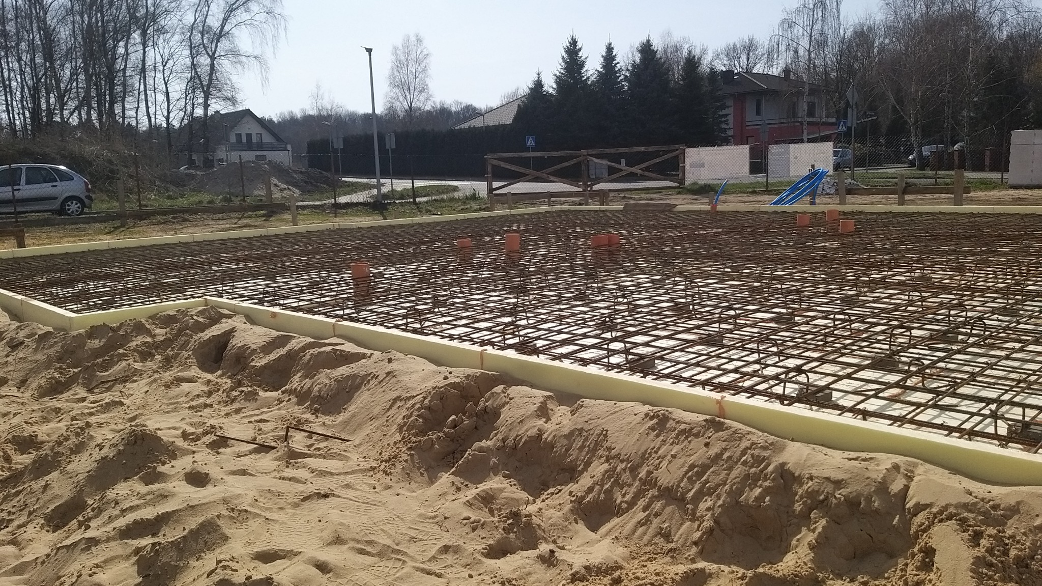 Przygotowanie zbrojenia pod płytę fundamentową we Włocławku, z widoczną izolacją obwodową i wystającymi rurami kanalizacyjnymi.