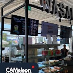 CAMeleon Monitoring - Ekran monitoringu w kawiarni z widocznym menu i ofertą, z logo firmy monitoringowej w rogu kadru.