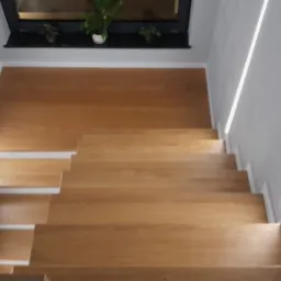 Schody dębowe w naturalnym kolorze z białą podstopnicą i listwą cokołową również w kolorze białym