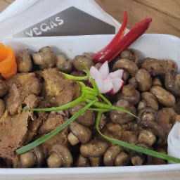 Danie cateringowe: duszone mięso z pieczarkami, dekorowane rzodkiewką, marchewką i papryczką chili, serwowane w białej misce z serwetkami 'Vegas' w tle.