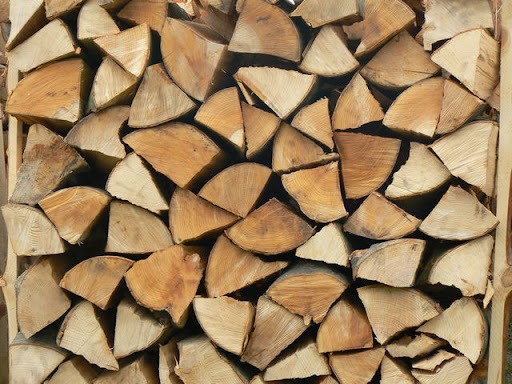 Równomiernie ułożone, porąbane kawałki drewna z widocznymi słojami, przygotowane do użycia jako opał.