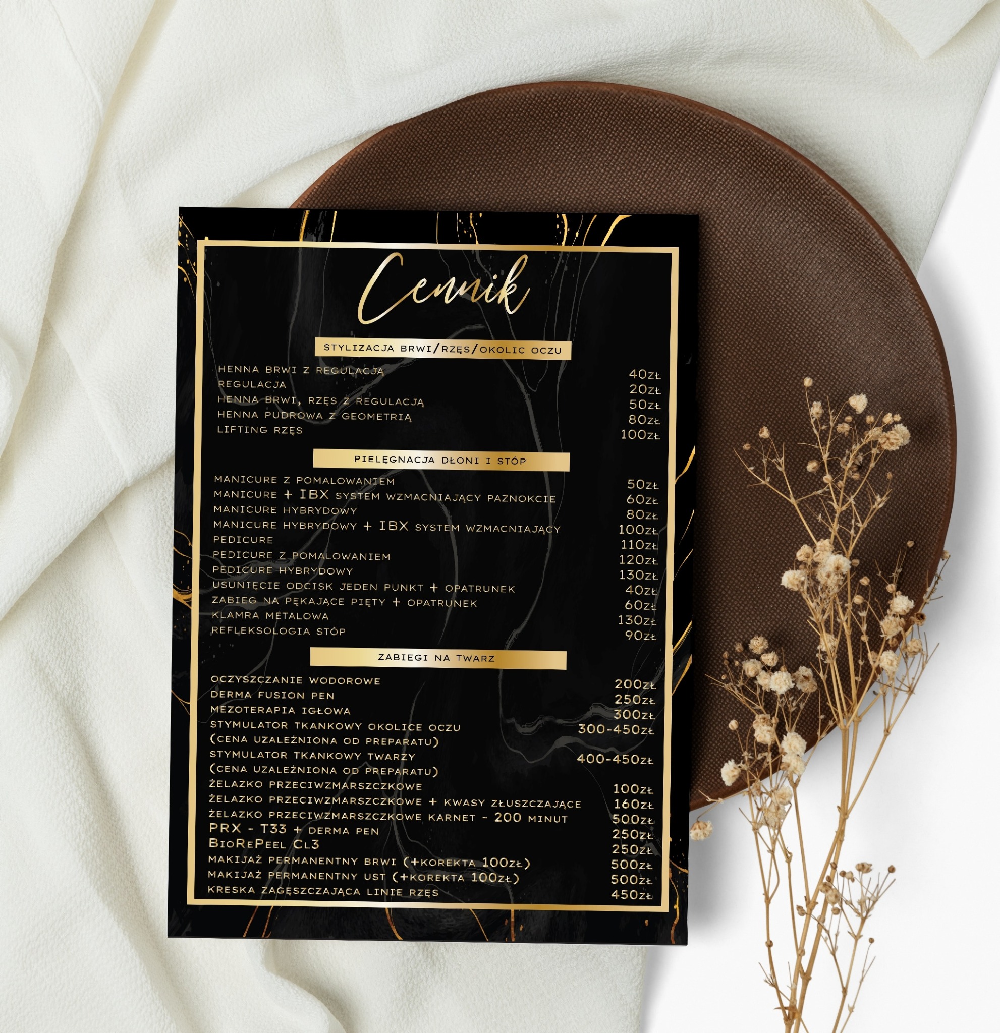 Elegancko zaprezentowany cennik usług kosmetycznych na czarnym tle z marmurkowym wzorem i złotymi akcentami, umieszczony obok suszonych kwiatów i kremowej tkaniny.