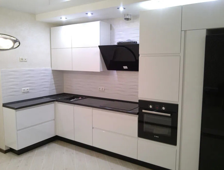 Nowoczesna biała kuchnia z czarnymi blatami, minimalistyczna zabudowa z piekarnikiem, czarny okap i lodówka, panel ścienny z efektem falowania, drewnopodobna podłoga.