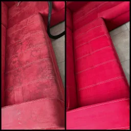 Czerwona sofa z widoczną różnicą przed i po czyszczeniu tapicerki, po lewej stronie widoczne plamy i zabrudzenia, po prawej czysta powierzchnia z jasnymi przeszyciami, obok węża odkurzacza.