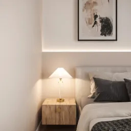 Minimalistyczna sypialnia z beżowymi ścianami, obrazem w czarnej ramie, podświetleniem LED nad wezgłowiem łóżka, drewnianą szafką nocną i lampką z białym kloszem.