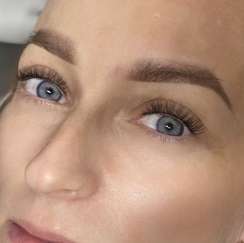 Zbliżenie na kobiece oko z wyraźnie podkreślonymi, gęstymi rzęsami po zabiegu przedłużania; widoczne również brwi po stylizacji.