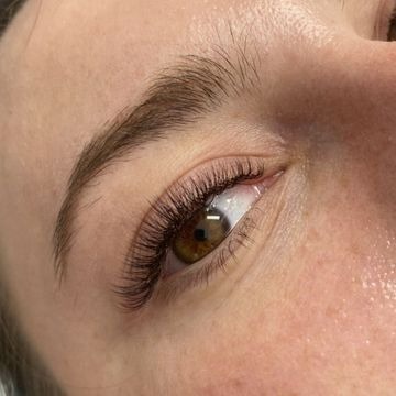 Zbliżenie na oko z przedłużonymi, brązowymi rzęsami metodą objętościową, widoczna naturalna brew i delikatny makijaż oka.