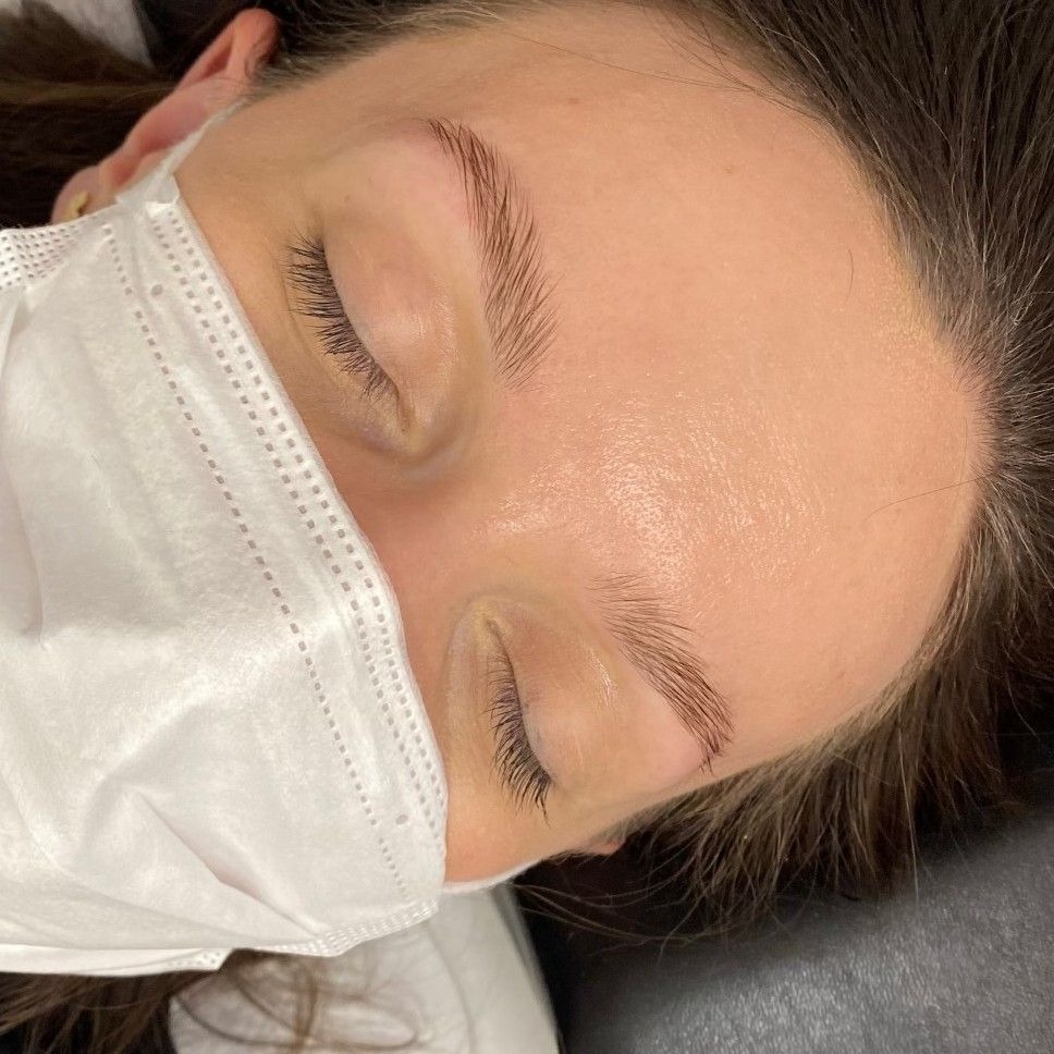 Klientka w masce ochronnej po zabiegu laminacji brwi, widoczne idealnie ułożone i błyszczące włoski brwi.