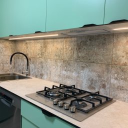 Dawid Ronek - Nowoczesna kuchnia z miętowo-zielonymi szafkami, beżowym blatem, płytą gazową Whirlpool i zlewozmywakiem dwukomorowym pod czarną baterią.