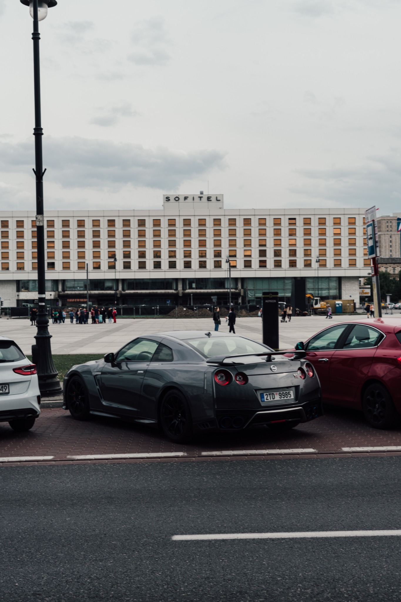 Szary Nissan GT-R zaparkowany na tle hotelu Sofitel w Warszawie, widok z tyłu, z widoczną tablicą rejestracyjną.