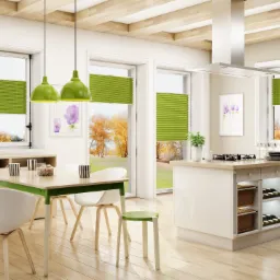 Jasne wnętrze kuchni z jadalnią, okna z zielonymi plisowanymi osłonami, widok na jesienny ogród.