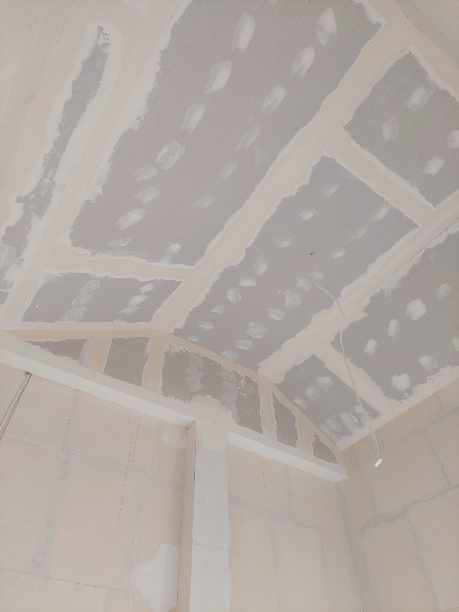 Sufit i ściany wykończone płytami kartonowo-gipsowymi, widoczne łączenia szpachlowane, przygotowane do dalszych prac wykończeniowych.
