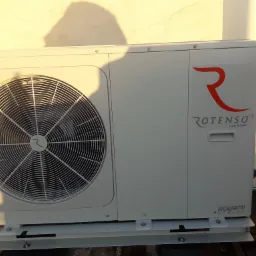 Zewnętrzna jednostka pompy ciepła Aquami Series zainstalowana w Borównie, z widocznym wentylatorem i logo Rotenso, oświetlona popołudniowym słońcem.