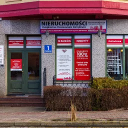 Fasada budynku z szyldem agencji nieruchomości oferującej kredyty bankowe, widoczne ogłoszenia o kredytach gotówkowych i hipotecznych, adres Starowałowa 1.