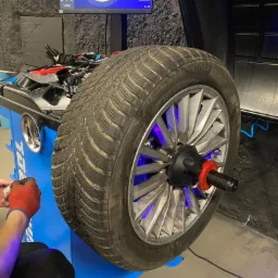 Wyważanie koła zimowego Bridgestone na maszynie z podświetleniem LED i ekranem diagnostycznym w warsztacie.