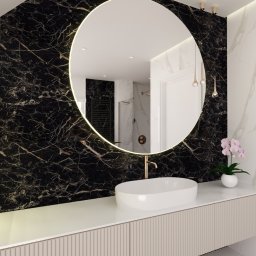 Studio Vermilion Anna Cisło - Nowoczesna łazienka z okrągłym lustrem podświetlanym LED, umywalką nablatową i ścianą wyłożoną czarnym marmurem z wyraźnym użyleniem.