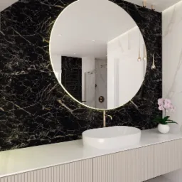 Nowoczesna łazienka z okrągłym lustrem podświetlanym LED, umywalką nablatową i ścianą wyłożoną czarnym marmurem z wyraźnym użyleniem.