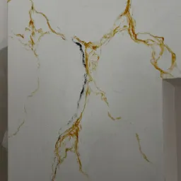 Ściana w trakcie wykańczania w Piasecznie z efektem imitacji marmuru z brązowymi i czarnymi żyłkami na jasnym tle, widoczne niedoskonałości i fragment futryny.