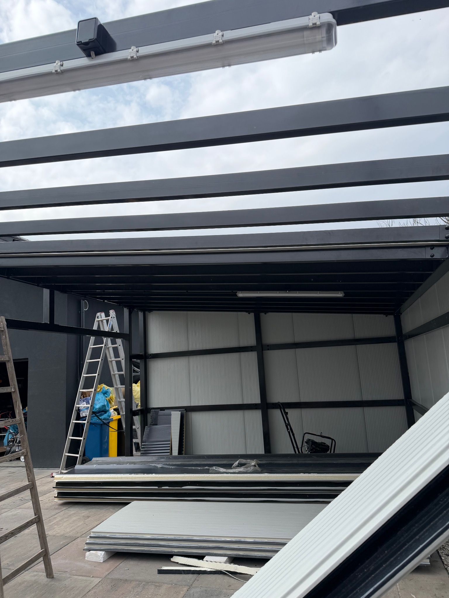 Montaż konstrukcji stalowej z profili zamkniętych, widoczny pracownik w kombinezonie ochronnym i elementy konstrukcyjne w hali. Prace montażowe w toku.