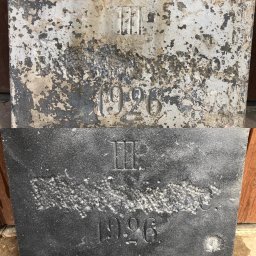 K&M Stolarstwo i Rzemiosło z Pasją Kachel Marcin - Porównanie powierzchni kamiennej płyty z wyrytym napisem '1926' przed i po renowacji: górna część z łuszczącą się farbą i zabrudzeniami, dolna część oczyszczona, pokryta ciemną powłoką.