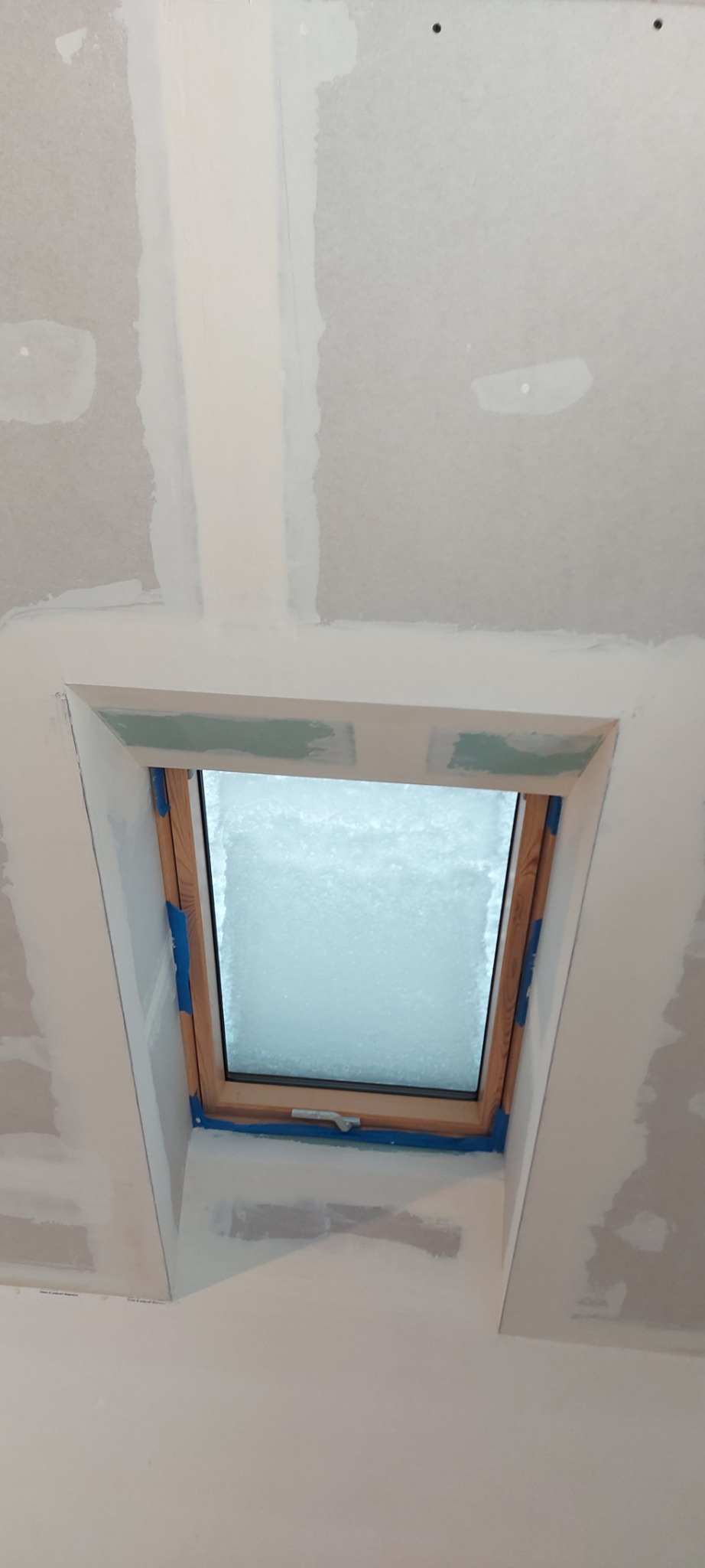 Okna dachowe w trakcie montażu, obróbka gipsowa, widoczne łączenia płyt kartonowo-gipsowych przed szpachlowaniem, zabezpieczone taśmą malarską.