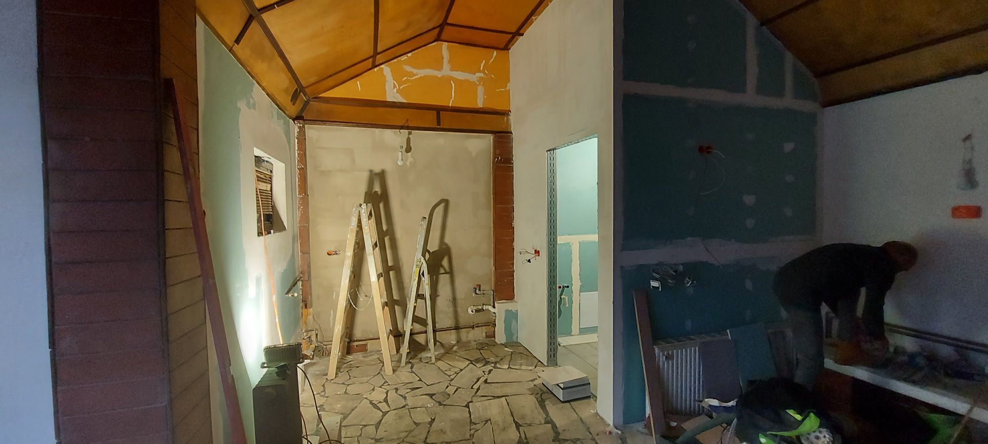 Wnętrze w trakcie remontu: widoczne drabiny, położona instalacja elektryczna, ściany przygotowane pod prace wykończeniowe, fragment podłogi z nieregularnych płytek, sufity z drewnianymi elementami,...