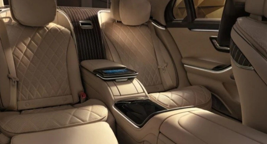 Luksusowe wnętrze samochodu z beżową skórzaną tapicerką w romby, podświetlanym panelem dotykowym i ekranem dla pasażerów z tyłu.