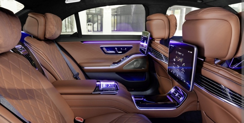 Luksusowe wnętrze samochodu z brązową skórzaną tapicerką, systemem rozrywki dla pasażerów z tyłu i nastrojowym oświetleniem LED.