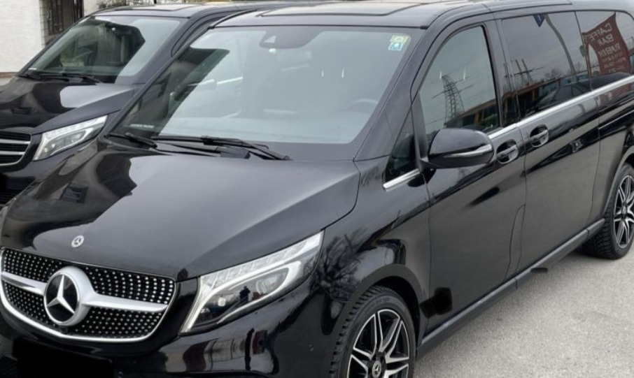 Dwa czarne busy Mercedes-Benz V-klasy zaparkowane obok siebie, widok z przodu na pierwszy pojazd z wyraźnie widocznym logo marki.