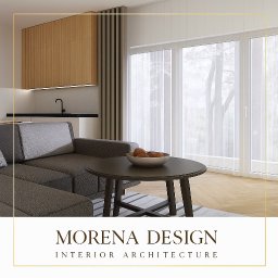 Morena Design - Jasne wnętrze z szarą sofą narożną i okrągłym stolikiem kawowym z owocami. W tle widoczna zabudowa kuchenna i duże okna z widokiem na zieleń.