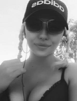 Czarno-białe zbliżenie kobiety w okularach przeciwsłonecznych i czapce z daszkiem, z warkoczami i kolczykami kołami.