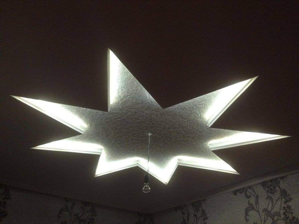 Dekoracyjny sufit w kształcie gwiazdy z podświetleniem LED, widoczne tapety na ścianach w tle.
