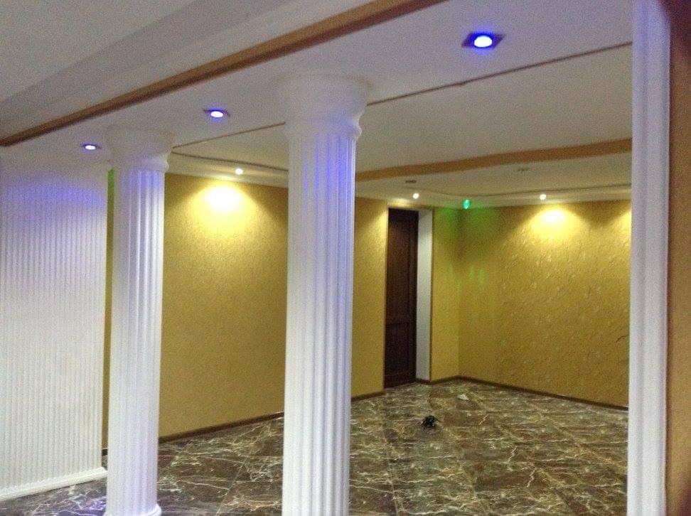 Wnętrze pokoju z marmurową podłogą, kolumnami z oświetleniem punktowym LED i ścianami w odcieniach złota.