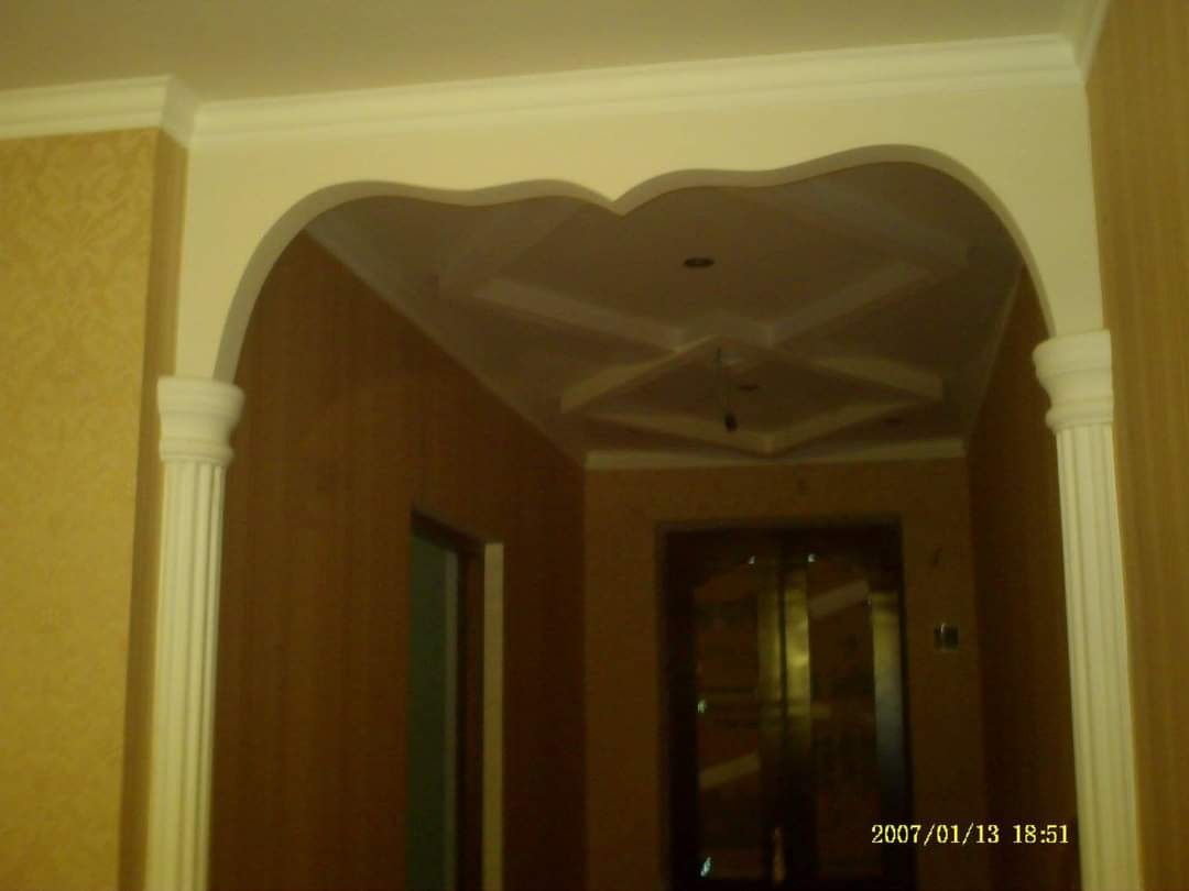 Arka z dekoracyjnymi kolumnami i ozdobnym sufitem w korytarzu, widoczny wzór na ścianie i data wykonania zdjęcia w rogu.