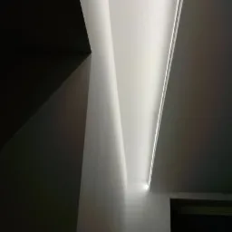 Nowoczesne oświetlenie sufitowe LED w mieszkaniu w Krakowie, z widoczną drabiną malarską w rogu pokoju.