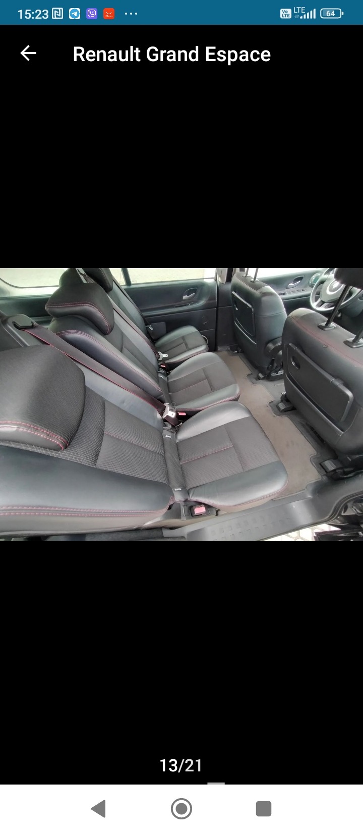 Wnętrze przestronnego samochodu typu van z trzema rzędami czarnych skórzanych foteli z czerwonymi przeszyciami, widok z tyłu kabiny.